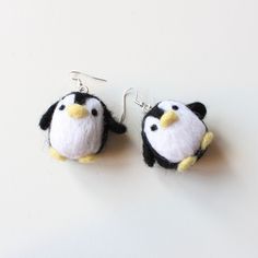 two small stuffed penguins are hanging from earrings