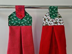 two red and green christmas towels hanging on a clothes line with one folded in the shape of a house