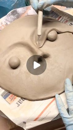 a person is making a clay face on a piece of pottery