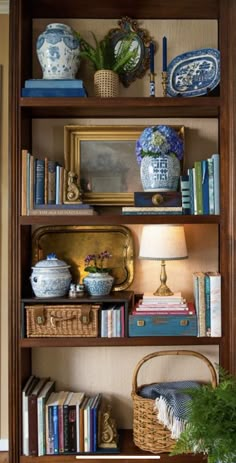 a bookshelf filled with lots of books and vases on top of it