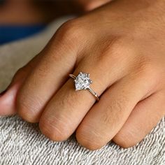 a close up of a person's hand with a diamond ring on their finger