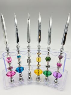 six different colored jeweled knives in a clear holder