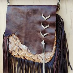 Channel the spirit of the Southwest with this boho handbag from Jewelry Junkie! Featuring a bold, Chateau print, this crossbody bag is sure to leave an impression. Made from genuine leather Fully lined Zipper closure Comes with a matching crossbody leather strap 36" long Measures 10” x 9” with a 10” leather fringe Genuine leather flap with raw cowhide edge Suede Lacing on the front of the flap Handmade and sourced in Texas, so no two bags are ever identical Embossed pattern evokes images of the Bohemian Crossbody Saddle Bag For Everyday Use, Hand Tooled Crossbody Satchel, Bohemian Saddle Shoulder Bag For Travel, Artisan Crossbody Shoulder Bag With Adjustable Strap, Leather Hobo Bag Crossbody For Festival, Bohemian Saddle Bag With Adjustable Strap For Travel, Leather Crossbody Hobo Bag For Festivals, Artisan Crossbody Saddle Bag With Adjustable Strap, Artisan Saddle Bag With Adjustable Strap