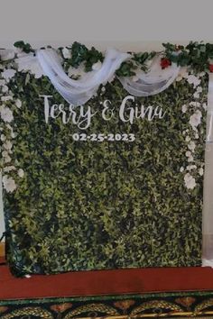 the wedding backdrop is decorated with greenery and white flowers on display at the reception