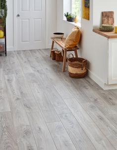 a room with white walls and wood floors, including a wooden bench in front of the door