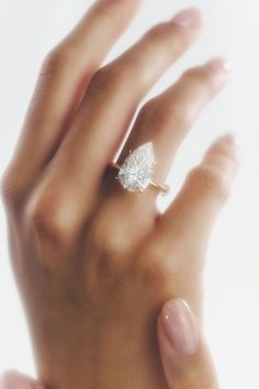 a woman's hand with a diamond ring on top of her left hand, against a white background