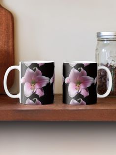 two coffee mugs sitting on top of a wooden shelf next to a glass jar