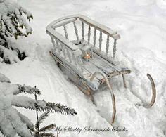 an old sled sitting in the snow next to some fir trees and pine cones