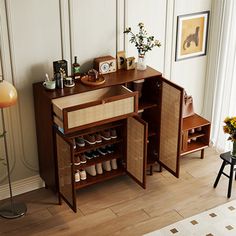 a wooden cabinet with shoes and other items on it next to a lamp in a living room