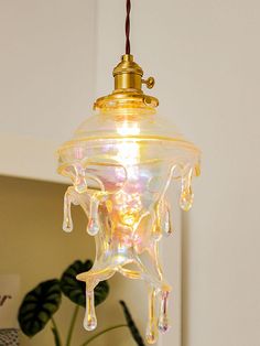 a glass light hanging from a ceiling in a room with a potted plant next to it