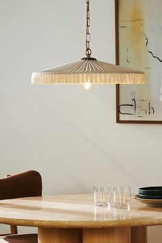 a dining room table with glasses on it and a light hanging from the ceiling over it