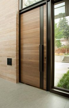 a large wooden door sitting next to a tall glass window on top of a building