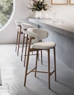 four bar stools are lined up in front of a counter with flowers on it