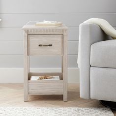 a small wooden table sitting next to a couch in a living room with a white rug on the floor