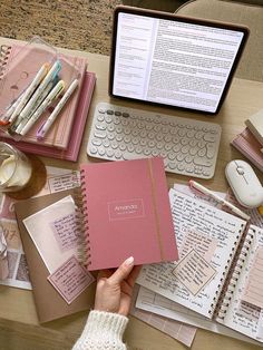 a person is holding a notebook in front of a laptop and papers on a desk