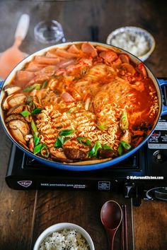 a large pan filled with food on top of a stove next to bowls and utensils