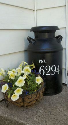 a large black urn sitting on the side of a house next to a flower pot