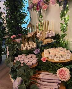 a table filled with cupcakes and flowers on top of wooden trays covered in greenery