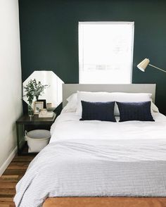 a bedroom with green walls and white bedding