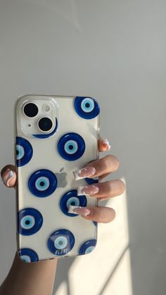 a woman holding up her phone case with blue circles on it