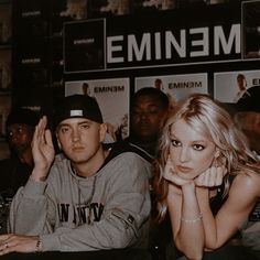 two people sitting next to each other in front of a sign