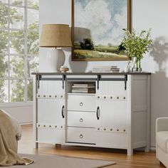 a living room with white furniture and a painting on the wall above it's dresser