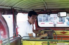 a man sitting in the driver's seat of an old truck with yellow paint