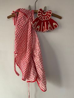 a red and white checkered cloth hanging from a wooden hanger on a wall