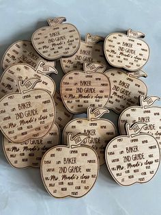 twelve wooden apple ornaments with names and words on them, all in different shapes and sizes