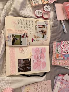 an open book sitting on top of a bed covered in pink and white paper next to other items