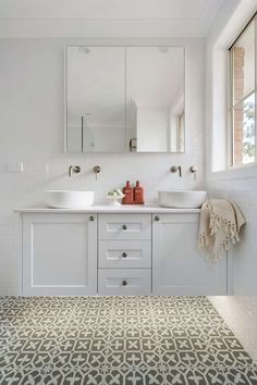 a white bathroom with two sinks and mirrors