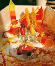 there are many small plastic objects in the bowl together, including candles and soaps