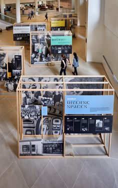 people are walking through an open building with posters on the walls and in front of them