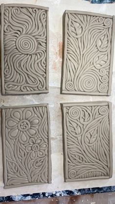 four square tiles are shown in the process of being carved with clay and ready to be painted