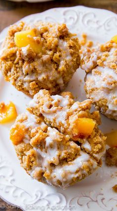 three muffins on a white plate topped with frosting and peaches are shown