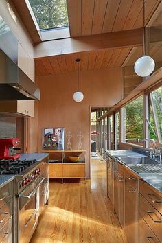 an open kitchen with wood floors and stainless steel counter tops, along with skylights