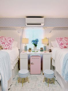 two twin beds in a bedroom with pink and blue decor on the nightstands next to each other