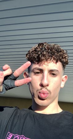 a young man making the peace sign with his hands while standing in front of a garage door