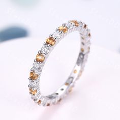 a white gold ring with citrine and diamonds on the side, sitting on top of a table