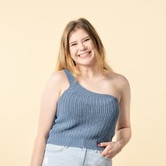 a woman in a blue top is smiling for the camera with her hands on her hips