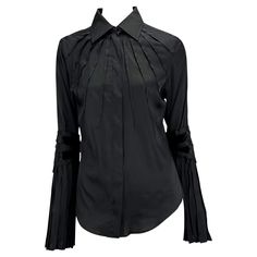 Presenting a black silk button-up Gucci shirt designed by Tom Ford. This incredible piece from the Fall/Winter 2004 collection is constructed of a silk-spandex blend and features pleats that jut from the neckline and elbow. The blouse is complete with black velvet ribbons that wrap part of the arms. From Ford’s final collection with Gucci, this piece can be worn day or night! Approximate measurements: Size -IT42 Shoulder to hem: 25” Bust: 36” Waist: 34” Shoulder to cuff: 26.5" Underarm to cuff:2 Black Gucci Top For Party, Gucci Formal Button-up Tops, Gucci Blouse, Gucci By Tom Ford, Goth Bedroom, Tom Ford Gucci, 00s Style, Gucci Shirt, Button Up Top