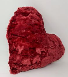 a red heart shaped pillow on a white background