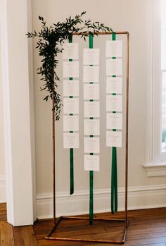 a table plan is set up on a metal stand with green ribbons and greenery