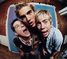 three young men standing next to each other in front of a tv screen with their mouths open