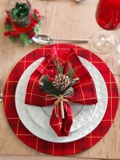 a place setting with red plaid napkins and pine cone centerpiece on the plate