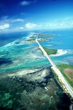 an aerial view of the ocean and road in the middle of it, with several islands on either side