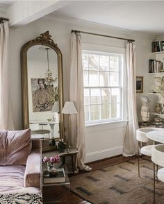 a living room filled with furniture and a large mirror on the wall next to a window