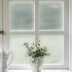 a vase filled with flowers sitting on top of a window sill next to a watering can