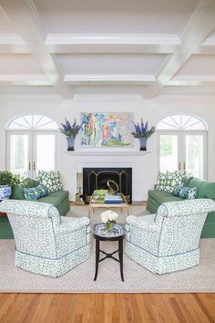 a living room filled with green couches and chairs next to a white fire place