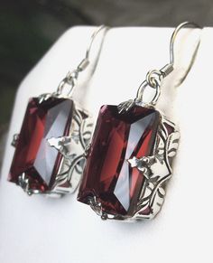 Simulated Red Ruby Earrings GL Design#15 Custom Made Earrings (E15) This is a brand new beautiful Art Deco-inspired filigree sterling silver pair of red ruby earrings. The gorgeous 16 carat simulated man-made ruby colored stones are flawless and vibrant. The stunning emerald-cut gemstones are 16mm (5/8") by 12mm (1/2"). The earrings are marked 925 for sterling and overall are 1-5/16" long. The beautiful blend of angle with swirl craftsmanship in the silver filigree settings is vintage inspired. Sterling Silver Rectangular Gemstone Earrings, Red Rectangular Sterling Silver Jewelry, Classic Sterling Silver Rectangular Earrings, Rectangular Red Sterling Silver Jewelry, Sterling Silver Oblong Earrings For Gift, Silver Rectangular Stone Earrings For Formal Occasions, Oblong Jewelry With Matching Earrings For Gifts, Oblong Jewelry Set With Matching Earrings As Gift, Jewelry Set With Matching Earrings As A Gift